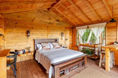 a bedroom with a bed in a wooden room at Cabaña Del Ermitaño entre los árboles del bosque de Efímero la Ceja in La Ceja