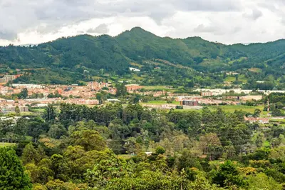 a town in a valley with mountains in the background at Cabaña Del Ermitaño entre los árboles del bosque de Efímero la Ceja in La Ceja