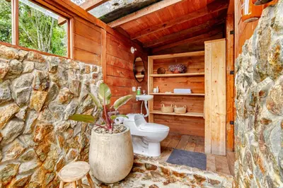 a bathroom with a toilet in a stone wall at Cabaña Del Ermitaño entre los árboles del bosque de Efímero la Ceja in La Ceja