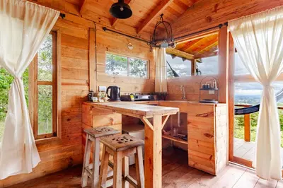 a kitchen in a log cabin with windows at Cabaña Del Ermitaño entre los árboles del bosque de Efímero la Ceja in La Ceja