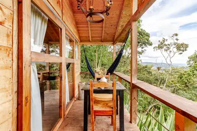 a wooden house with a table and chairs on a porch at Cabaña Del Ermitaño entre los árboles del bosque de Efímero la Ceja in La Ceja