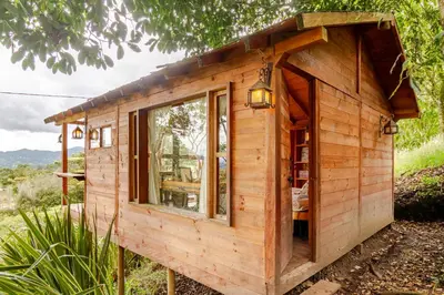 a small wooden house with a window at Cabaña Del Ermitaño entre los árboles del bosque de Efímero la Ceja in La Ceja