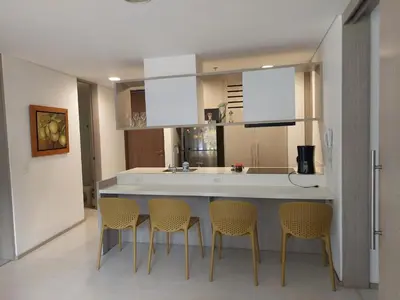 a kitchen with a bar with chairs and a counter top at Apartasuite en Rionegro, piscina, gimnasio y spa in Rionegro
