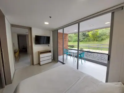 a bedroom with a bed and a balcony with a table at Apartasuite en Rionegro, piscina, gimnasio y spa in Rionegro