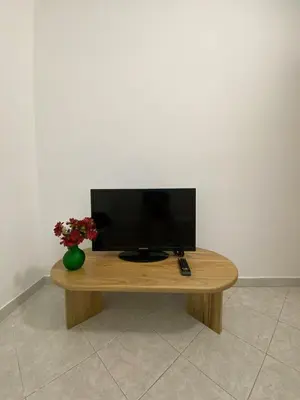 a television on a wooden table with a vase of flowers at Apartmento a una cuadra del aprque principal in San Rafael