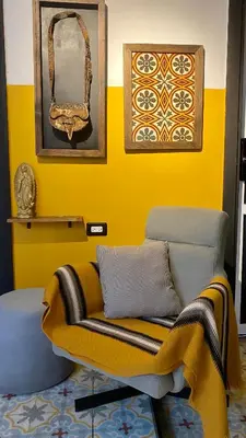 a living room with a couch and a yellow wall at Casa Mosaiko Sonsón in Sonsón