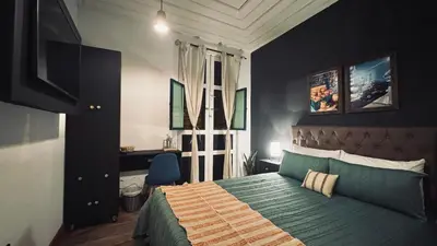 a bedroom with a bed and a desk and a window at Casa Mosaiko Sonsón in Sonsón