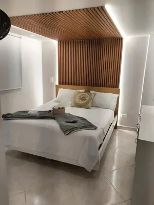 a bedroom with a large white bed with a wooden headboard at Tu espacio cómodo, elegante y céntrico con balcón 401 in Medellín
