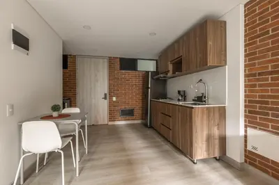 a kitchen with a table and chairs and a brick wall at Kyux Building, Style and Comfort in Medellín