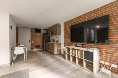 a living room with a large television on a brick wall at Kyux Building, Style and Comfort in Medellín