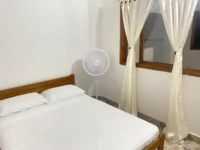 a bedroom with a bed and a fan and a window at Casa MAVA in Mariquita