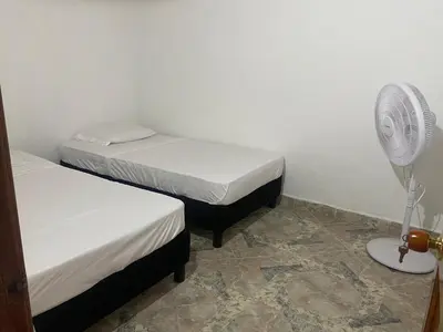 a small room with two beds and a fan at Casa MAVA in Mariquita