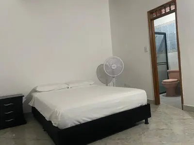 a bedroom with a white bed and a fan at Casa MAVA in Mariquita