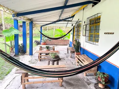 a hammock in a patio with benches and tables at Las Hamacas Mountain Hostal zona de camping in Villamaría