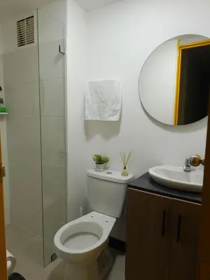 a bathroom with a toilet and a sink and a mirror at Apartamento cerca Terminal de Transportes y Cable aéreo in Manizales