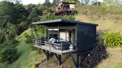 a black house sitting on top of a hill at Roots Eco House in Guatapé