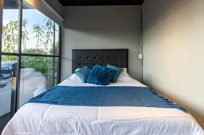a bedroom with a large bed with blue pillows at Roots Eco House in Guatapé