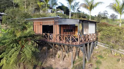 a tree house on a hill with palm trees at Roots Eco House in Guatapé