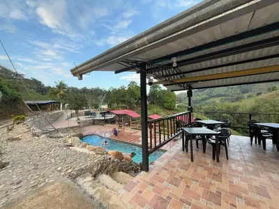 a patio with tables and a swimming pool with a roof at Cabaña con jacuzzi y piscina con agua de manantial in Norcasia