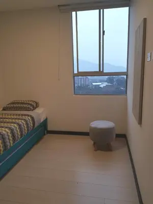 a bedroom with a bed and a stool in front of a window at Next to natural reserve, amazing views! in La Estrella