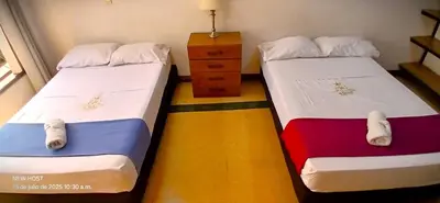 two twin beds in a room with a dresser at COMODO APARTAMENTO WIFI-COWORK CERCA a ZONA TURISTICA DE MEDELLIN in Medellín