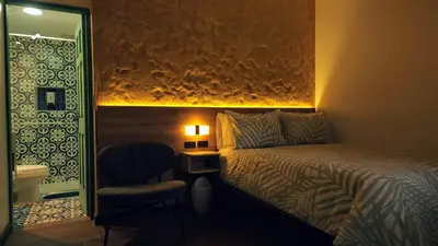 a bedroom with a bed and a chair and a mirror at Paraíso Plaza - Hotel Boutique in Aguadas