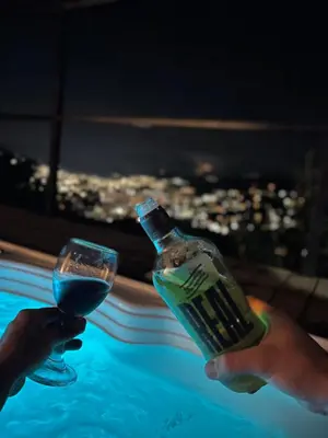 a person holding a bottle and a glass in a swimming pool at Cabañas DALI la catedral in Envigado