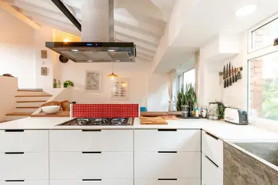 a kitchen with white cabinets and a red stove top oven at Homely Penthouse in Provenza in Medellín