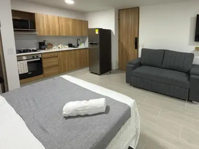 a room with a bed and a couch and a kitchen at Nuevo apartamento en plaza principal de Guatape in Guatapé