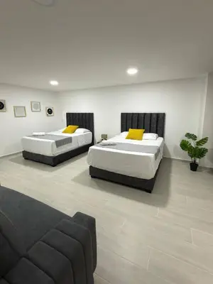 two beds in a room with a couch at Nuevo apartamento en plaza principal de Guatape in Guatapé
