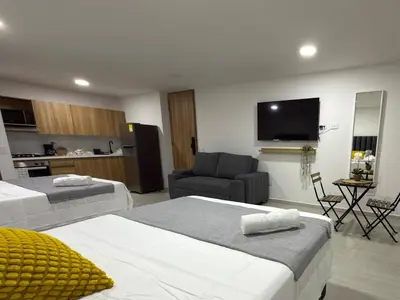 a hotel room with two beds and a television at Nuevo apartamento en plaza principal de Guatape in Guatapé