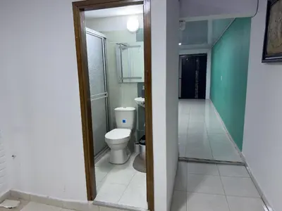 a bathroom with a toilet and a hallway at Laureles Coliving House Medellín in Medellín