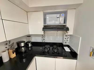 a kitchen with a stove and a microwave at Medellín Poblado Gem Steps to Cafés & Nightlife in Medellín