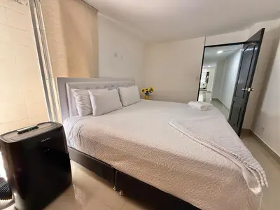 a bedroom with a large white bed with a mirror at Medellín Poblado Gem Steps to Cafés & Nightlife in Medellín
