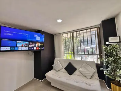 a living room with a white couch and a flat screen tv at Medellín Poblado Gem Steps to Cafés & Nightlife in Medellín