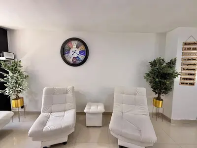 two white chairs and a clock on a white wall at Medellín Poblado Gem Steps to Cafés & Nightlife in Medellín
