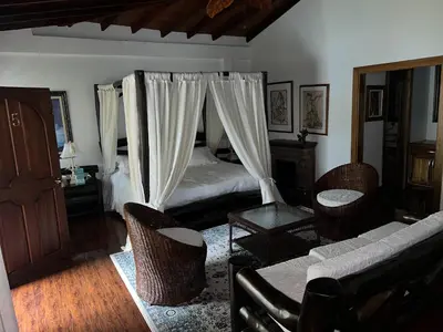 a bedroom with a bed with curtains and chairs at Casablanca Hotel Boutique Salamina in Salamina
