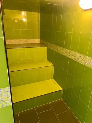a green tiled shower with yellow shelves at Casablanca Hotel Boutique Salamina in Salamina