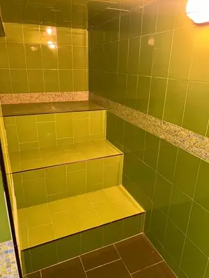 a green tiled shower with yellow shelves at Casablanca Hotel Boutique Salamina in Salamina