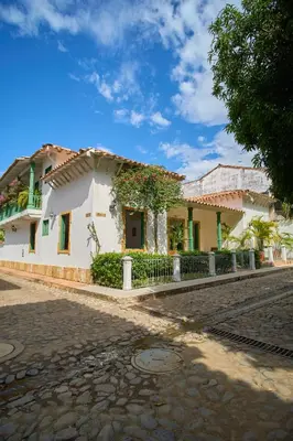a white house with a balcony on a cobblestone street at Cauca Viejo parque Aliciadorada in Jericó