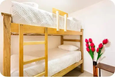 two bunk beds in a room with a vase of red flowers at Group Stay in Poblado - Walk Everywhere - King Bed in Medellín