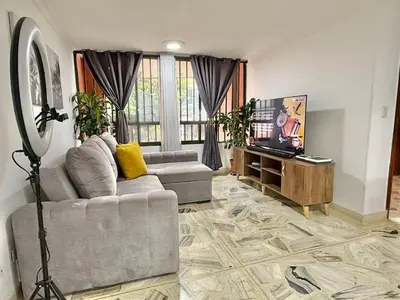 a living room with a couch and a tv in it at Poblado Gem Walk to Provenza and Steps to Cafes in Medellín