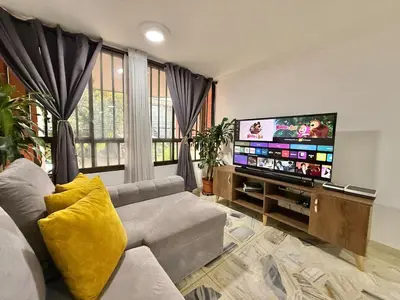 a living room with a couch and a flat screen tv at Poblado Gem Walk to Provenza and Steps to Cafes in Medellín