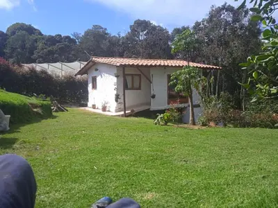 a small white house with a grass yard at Cabaña campestre in Medellín