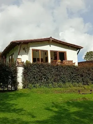 a small white house with a green yard at Cabaña campestre in Medellín