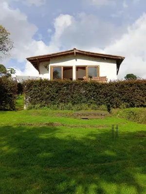 a house behind a hedge with a green yard at Cabaña campestre in Medellín