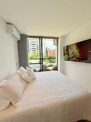 a bedroom with a white bed with a large window at Poblado de lujo in Medellín