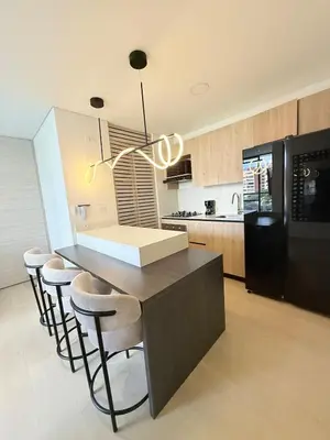 a kitchen with a counter with stools and a black refrigerator at Poblado de lujo in Medellín