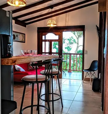 a kitchen with a bar with stools in a room at Country cabin with panoramic view among clouds - cabaña refugio entre nubes in Támesis