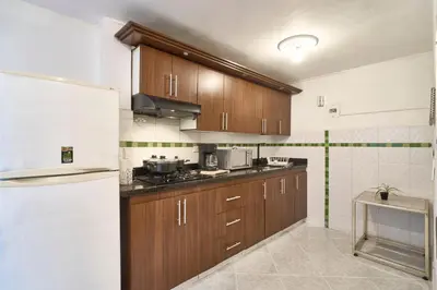 a kitchen with wooden cabinets and a refrigerator at Casa grande cerca al Poblado in Medellín